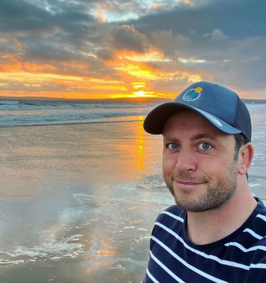 Man smiling at the beach during sunset.