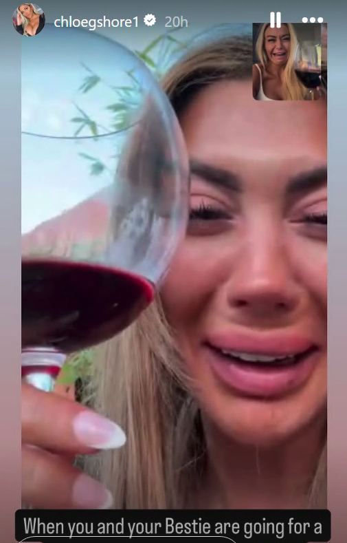 Woman crying while holding a glass of wine, video chatting with a friend.