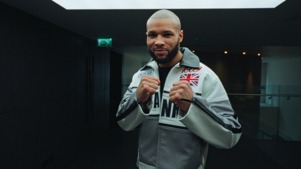 Chris Eubank in a boxing stance, wearing a white and grey jacket.