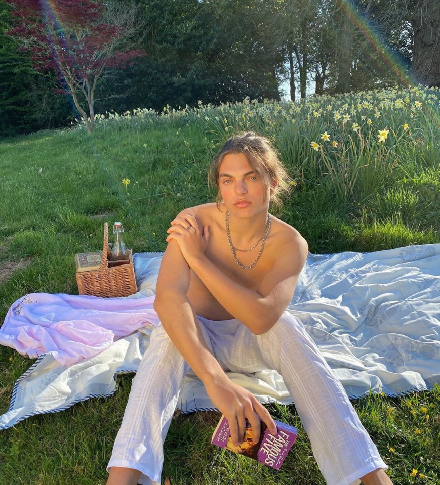 Person sitting on a blanket outdoors reading a book.