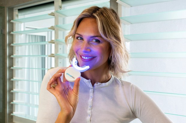 Woman using a SmilePro teeth whitening device.