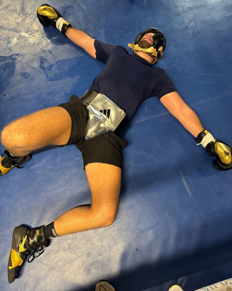 Boxer lying on his back in a boxing ring.