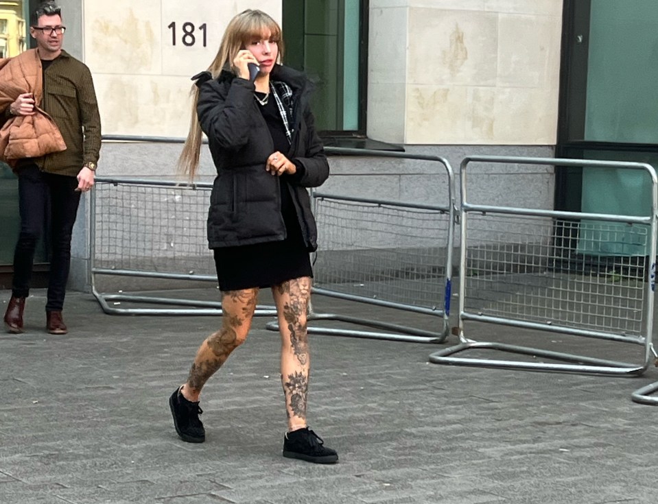 Woman with tattoos on her legs talking on a cell phone outside a building.