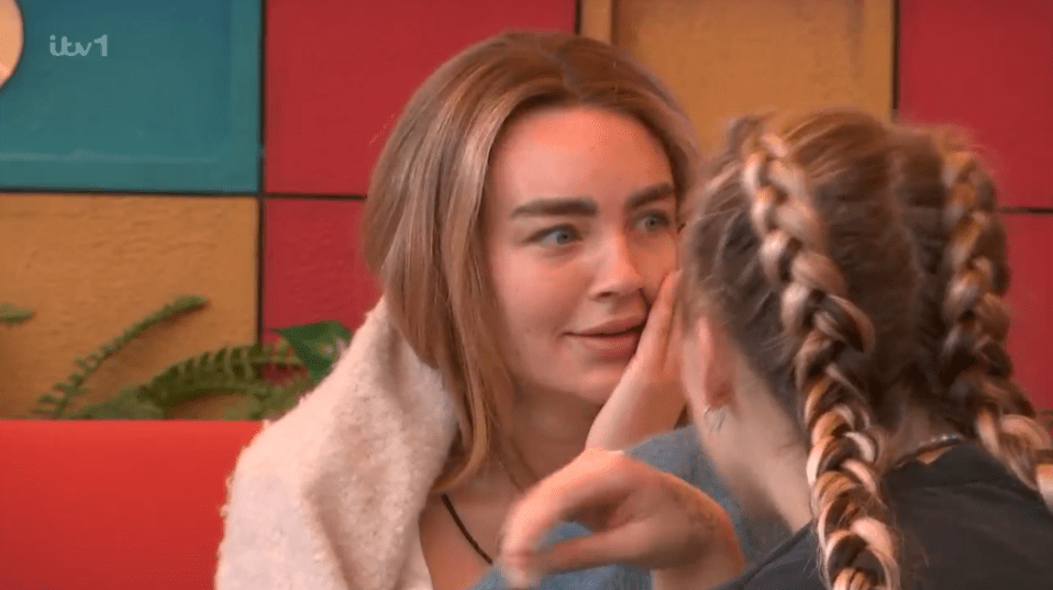 Two women whispering to each other.