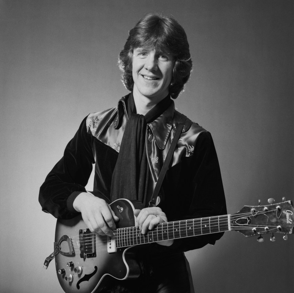 Black and white photo of Mike Berry playing a guitar.