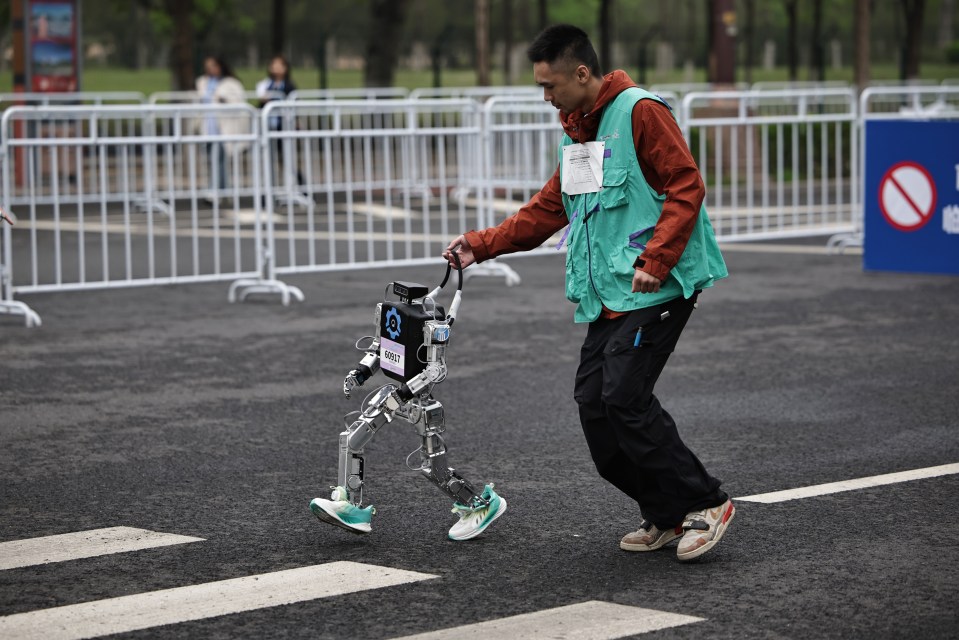 A person leads a humanoid robot during a marathon.