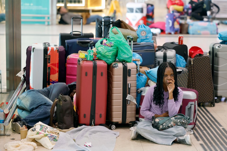 Passengers wait at a train station with their luggage due to a service disruption.