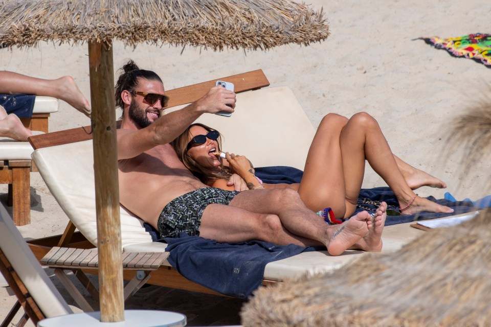 Andy Carroll and Lou Teasdale relaxing on beach loungers, taking a selfie.