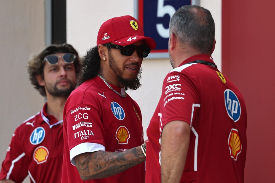Lewis Hamilton in Ferrari attire speaking with a teammate.