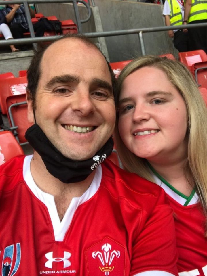 Selfie of a couple at a sporting event.  The man is wearing a Welsh rugby jersey.