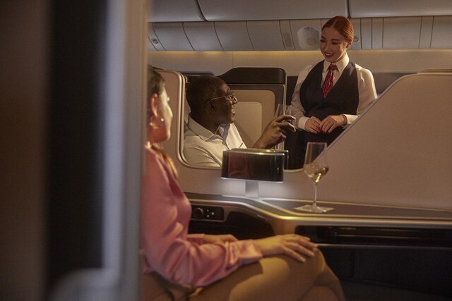 First-class passengers enjoying drinks with flight attendant.