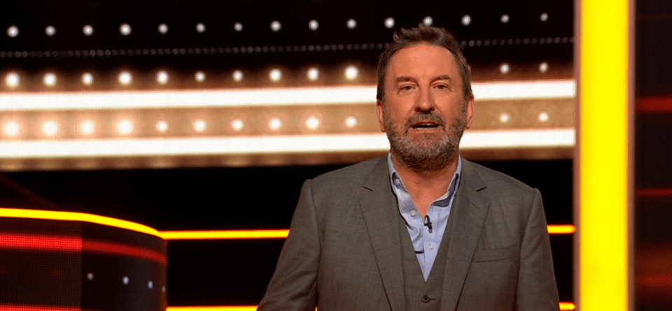 A man in a suit on a game show set.