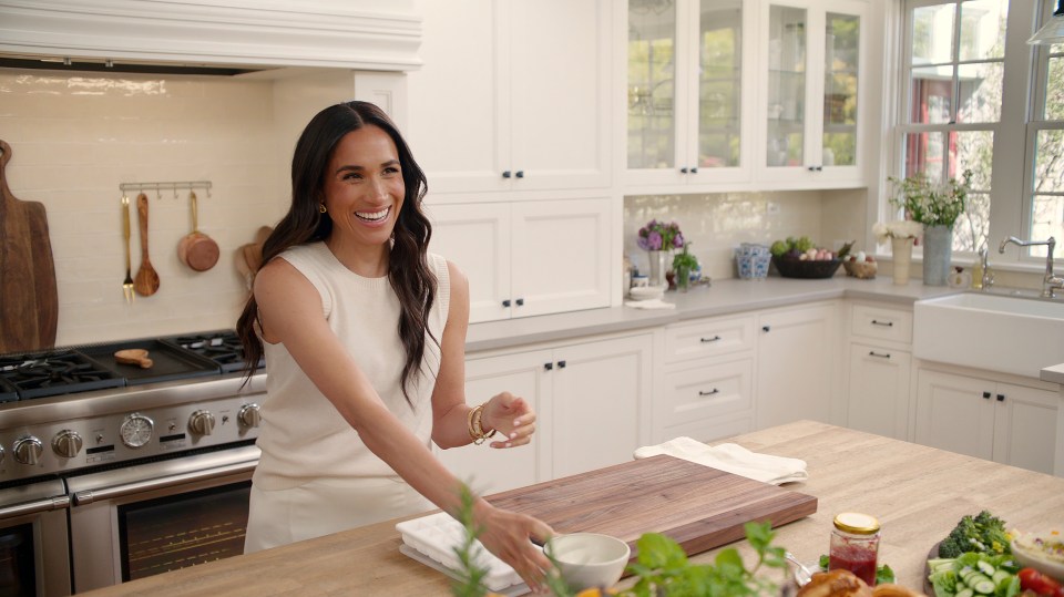 Meghan Markle in a white top in a kitchen.
