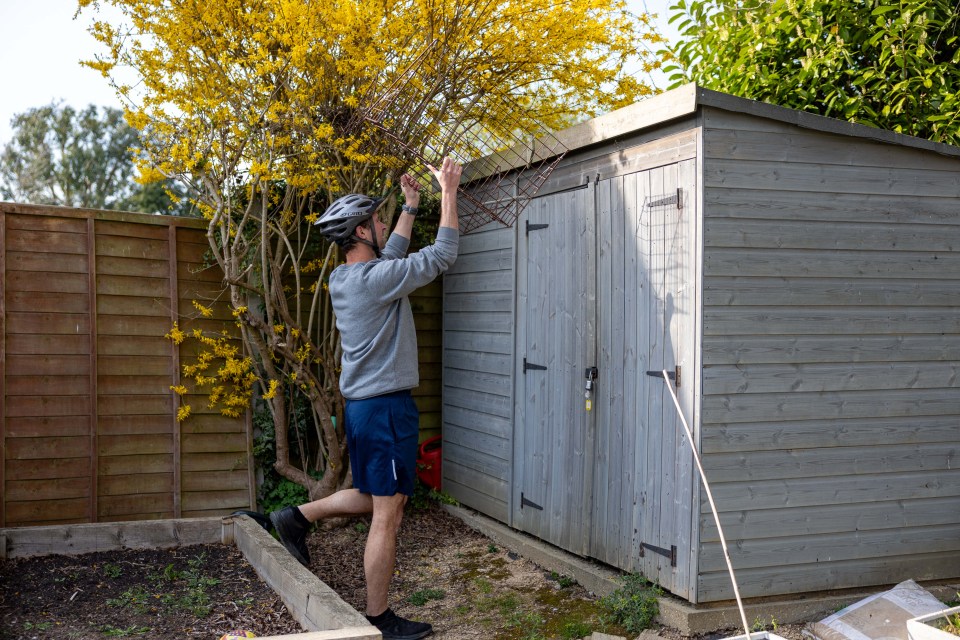 Man placing a wire cage on a shed.