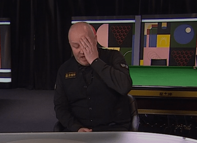 A man in a black shirt covers his face with his hand.