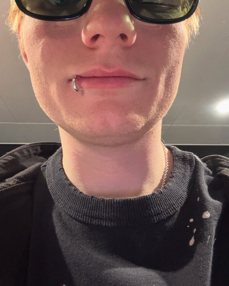 Close-up of a person with a lip piercing and sunglasses.