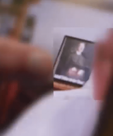 Blurry photo of a person holding a framed portrait.