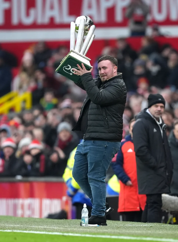 Man holding up a trophy on a soccer field.