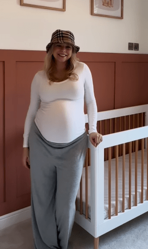 Pregnant woman standing by a crib.