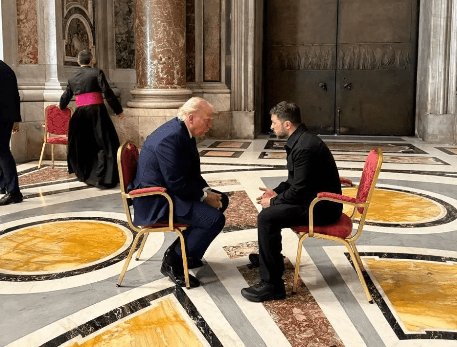 Donald Trump and another man sitting in chairs facing each other.