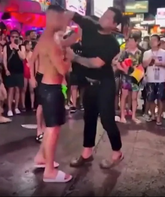 Two men fighting in a crowded street.
