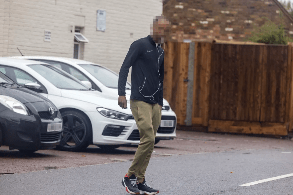 Man walking down a street with cars parked in the background.