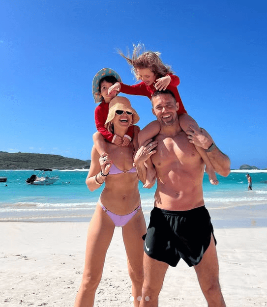 Family on a beach with two young children on their shoulders.