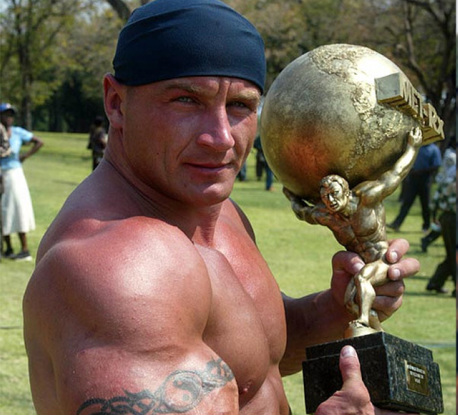 A muscular man holding a globe trophy.