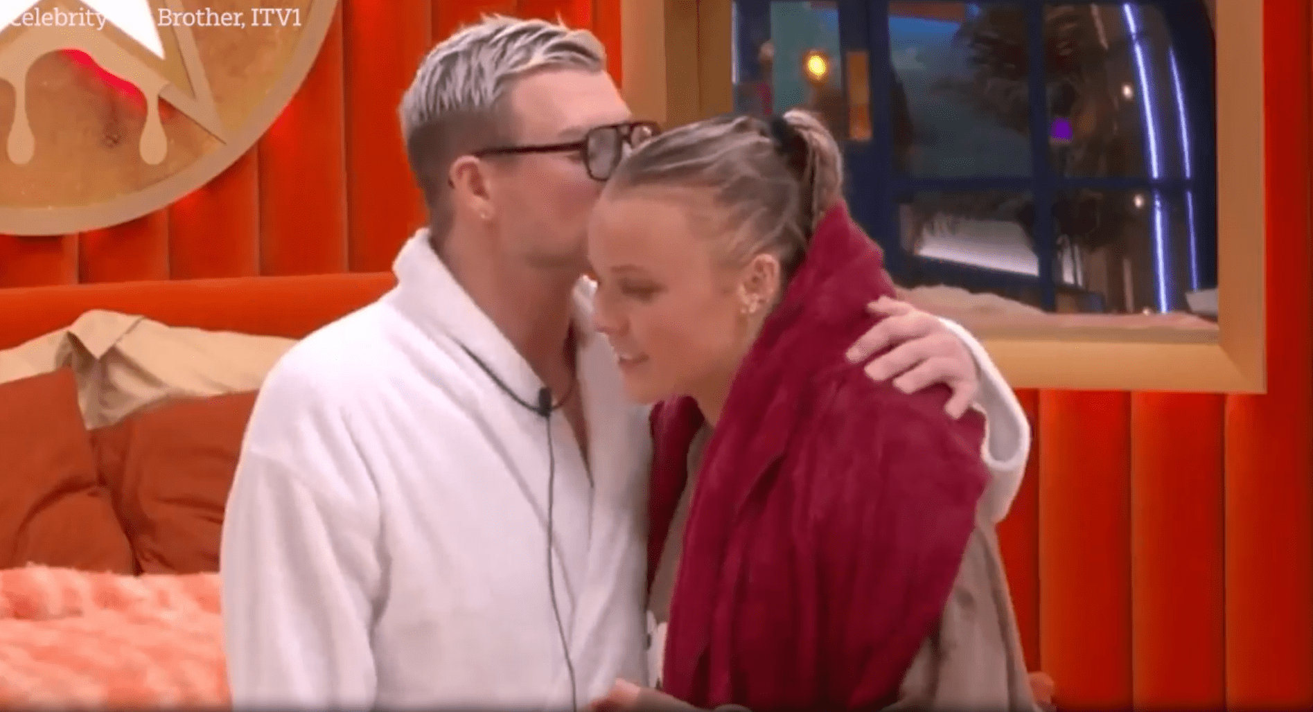 Man whispering to woman in bathrobes.