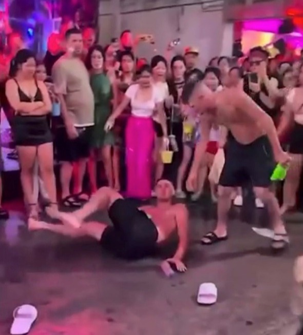 Man lying on the ground surrounded by people at a party.