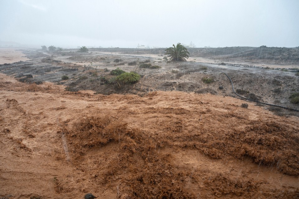 Floodwaters rushing through a dry landscape.