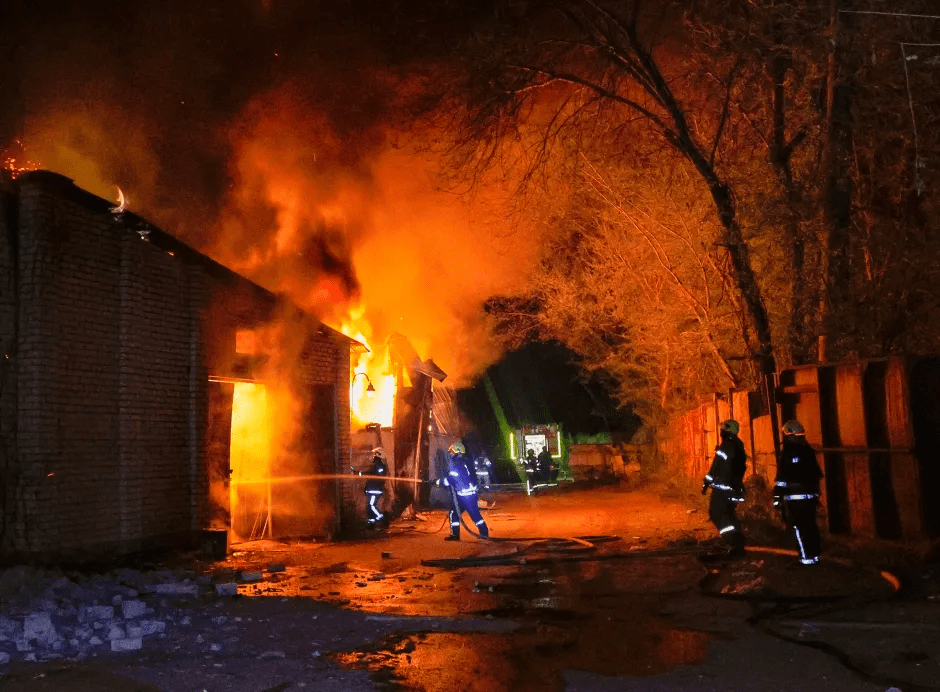 Firefighters battling a large building fire at night.
