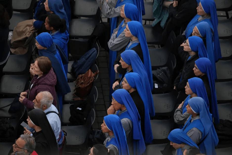 Nuns in blue habits seated in rows.