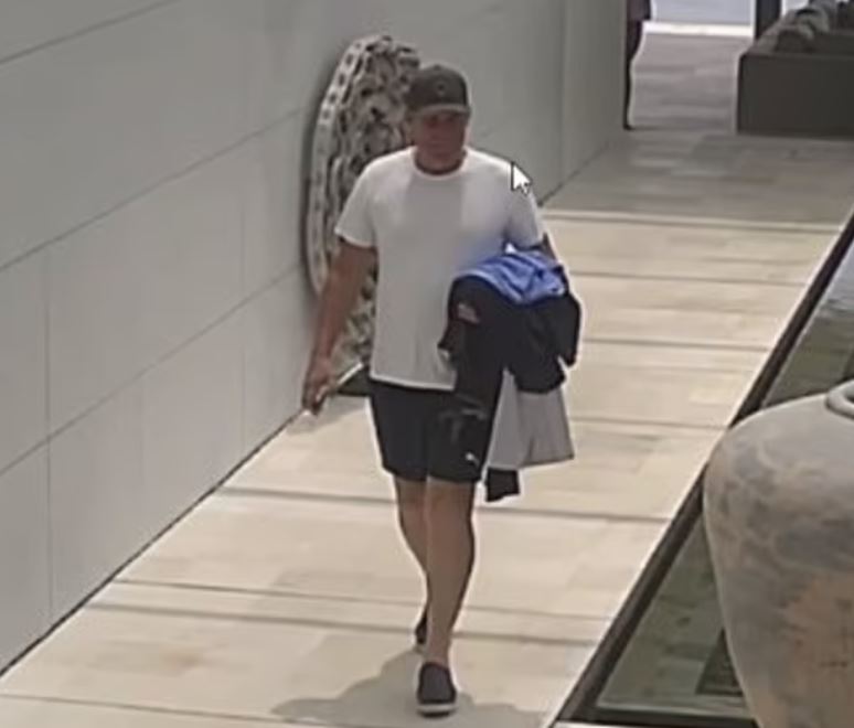 Man walking down hallway carrying clothes.