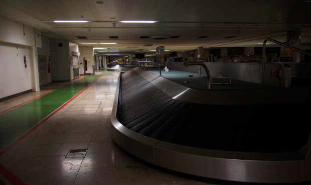 Empty baggage carousel in a dark airport terminal.