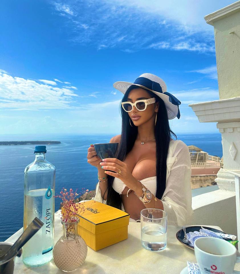Woman enjoying a drink on a balcony overlooking the ocean.