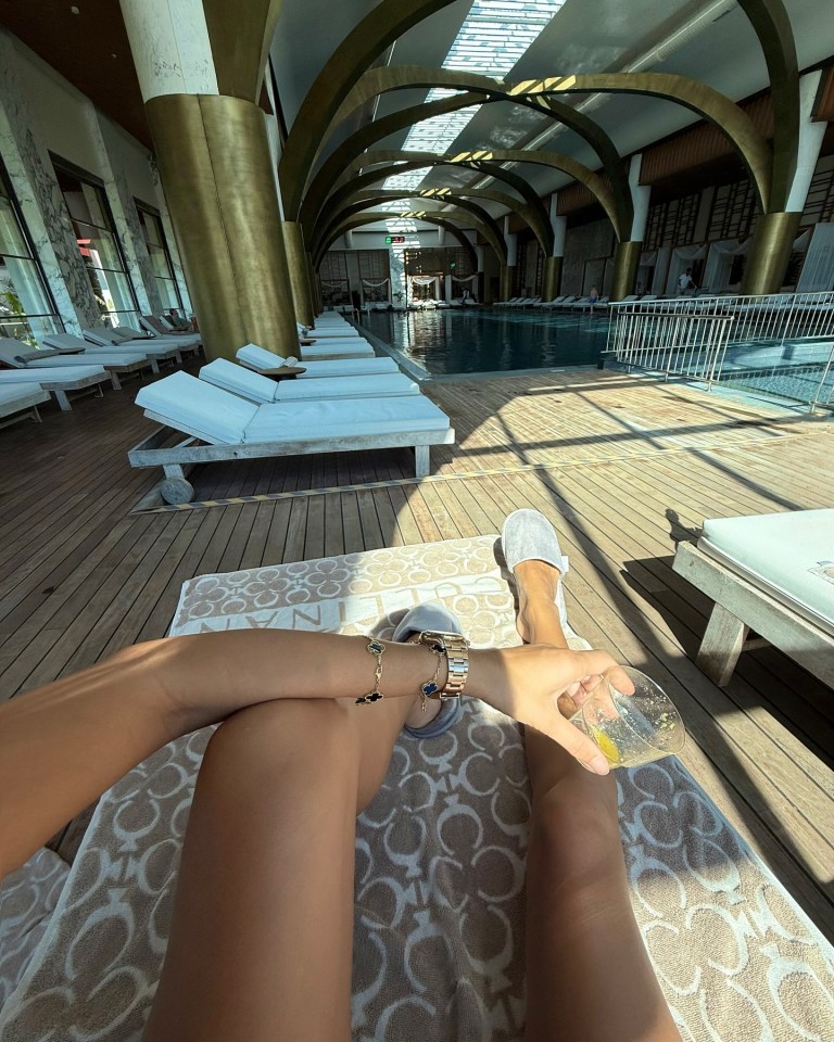 Person relaxing by a resort pool with a drink.