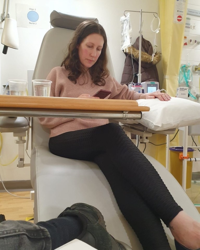 Woman sitting in a hospital chair using her phone.