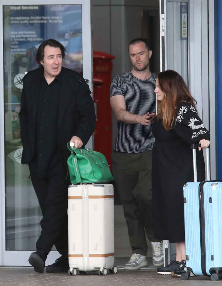 Jonathan Ross arriving at an airport with luggage.