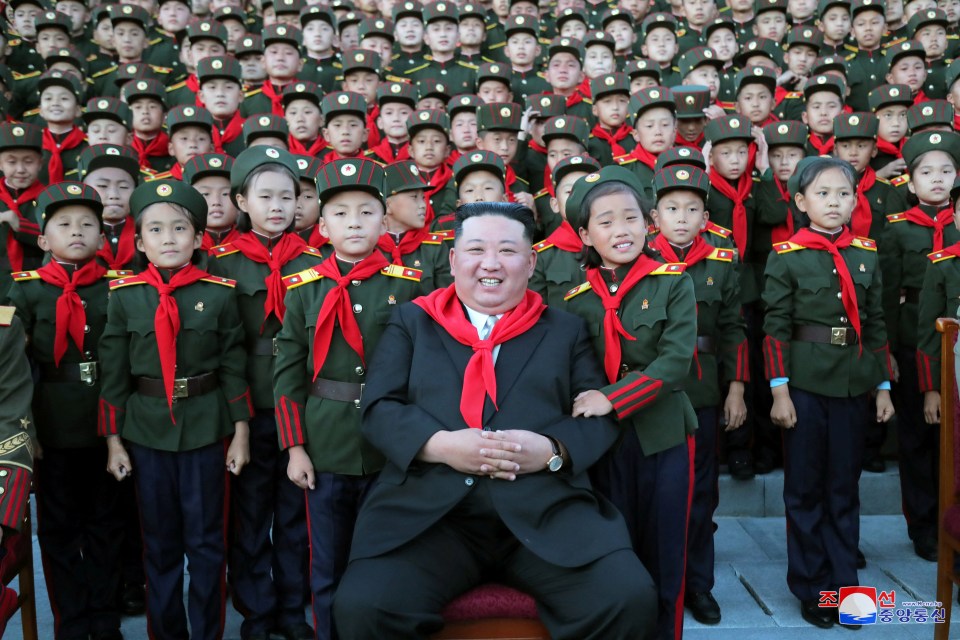Kim Jong Un with children in uniform at a ceremony.