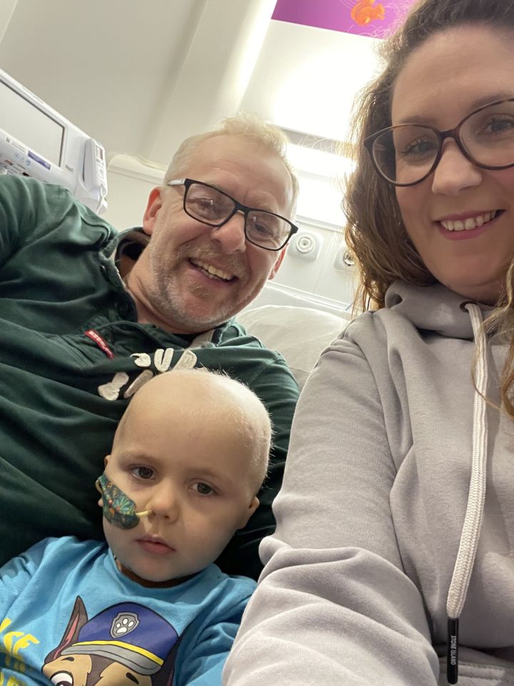 A family photo of a young boy with his parents in a hospital room.