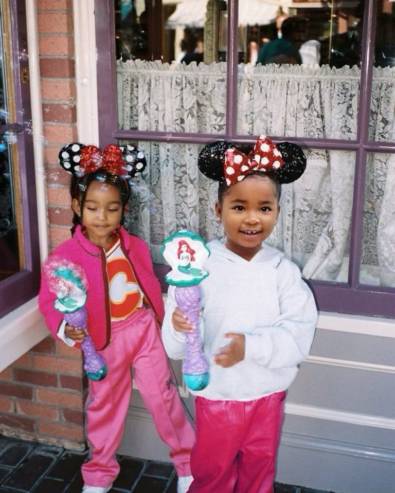 Two young girls with Minnie Mouse ears hold bubble wands at Disneyland.