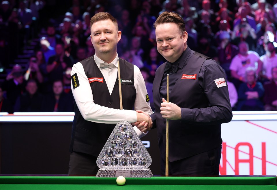 Kyren Wilson and Shaun Murphy shaking hands at a snooker tournament.