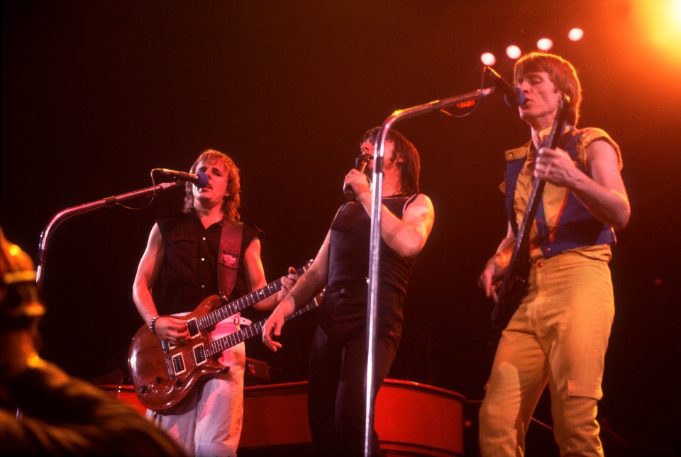 Journey band members Jonathan Cain, Steve Perry, and Ross Valory performing on stage.