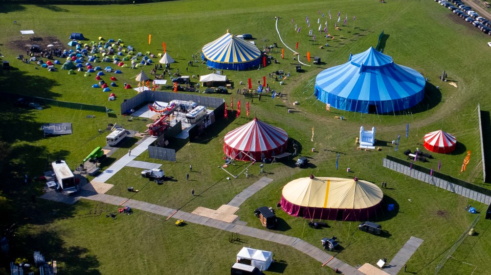 Aerial view of a film set with tents, vehicles, and equipment.