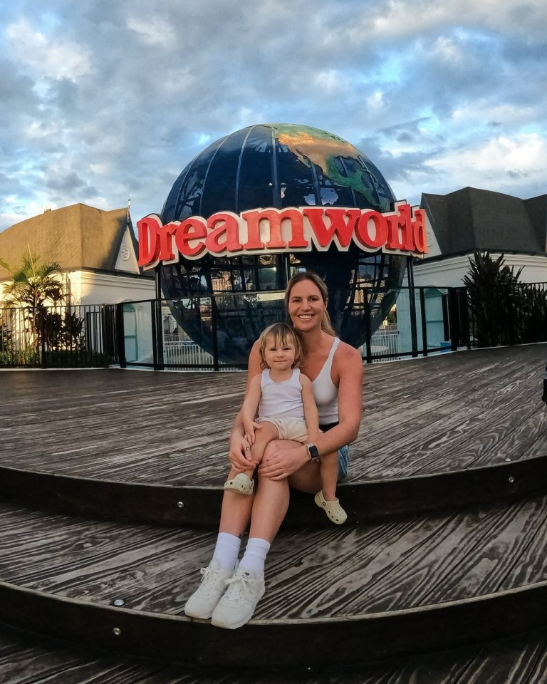 Woman and child sitting in front of Dreamworld globe.