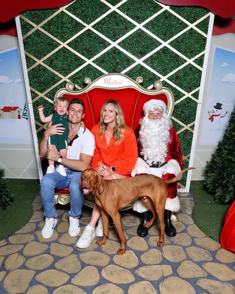 Family with dog posing with Santa Claus for a Christmas photo.