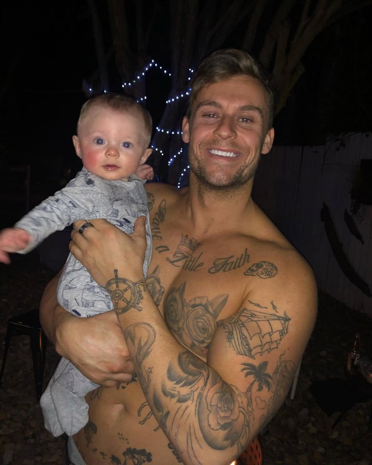 Man with tattoos holding a baby.