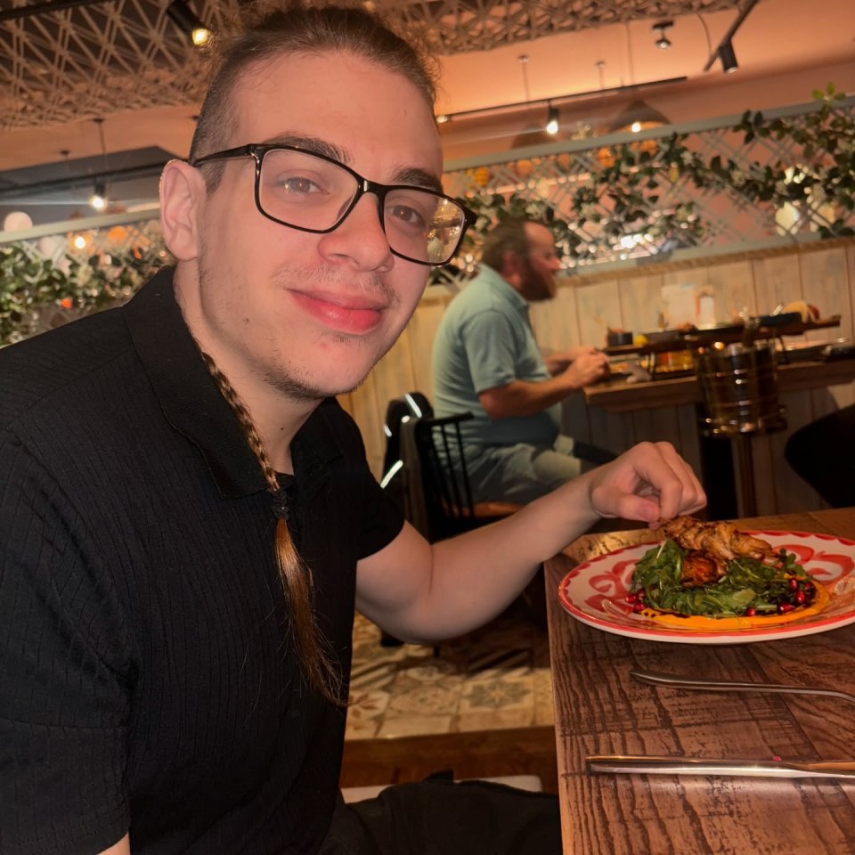 Man with glasses eating at a restaurant.
