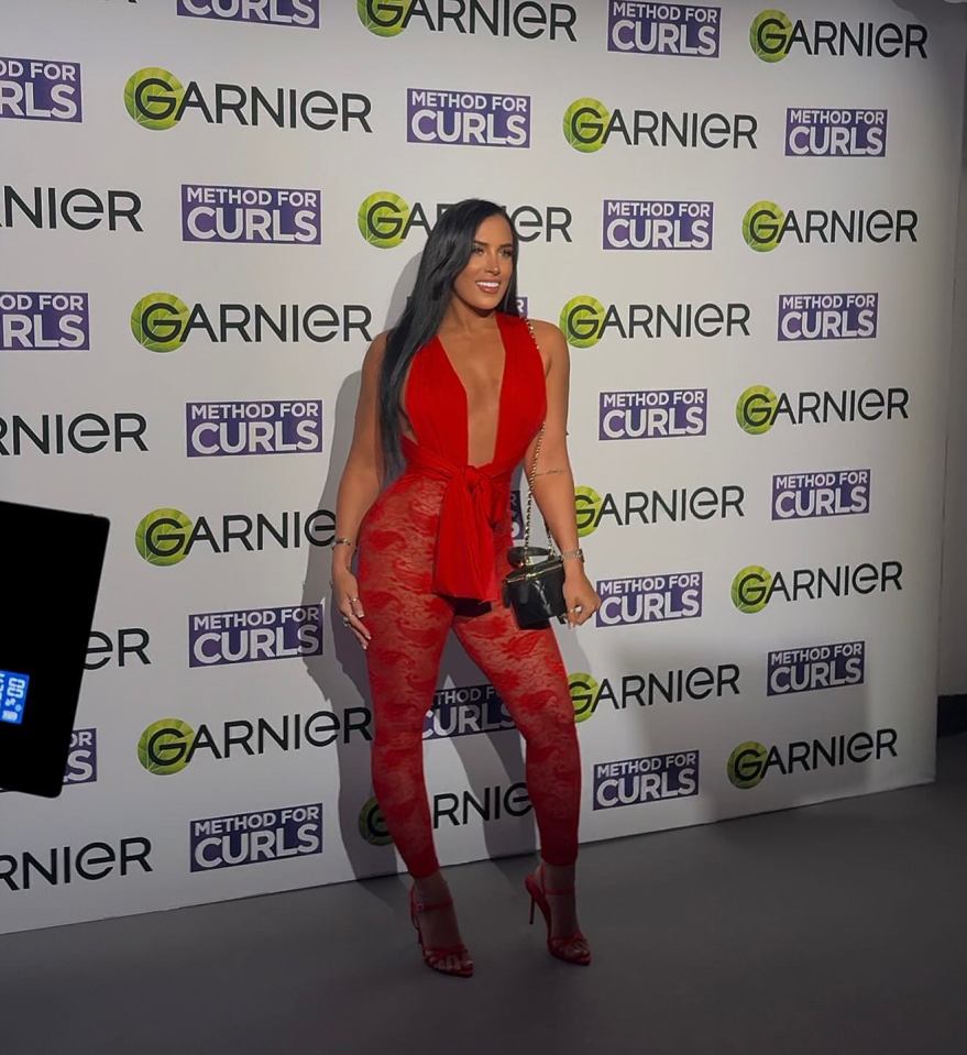 Woman in red lace jumpsuit at a Garnier event.